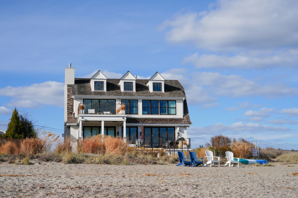 Beach chairs on the sand in front of a house